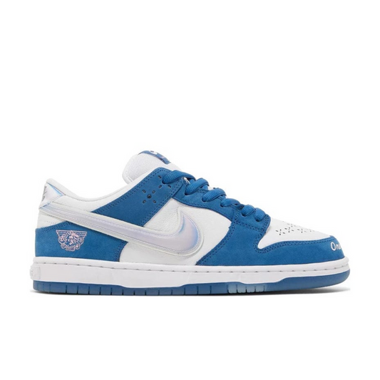 "Nike SB Dunk Low Born x Raised sneaker with white leather and deep royal blue nubuck overlays"

"Side view of Nike SB Dunk Low Born x Raised with holographic Swoosh and perforated toe box"

"Close-up of Nike SB Dunk Low Born x Raised showing embroidered text and heat-pressed laces"

"Nike SB Dunk Low Born x Raised – cultural tribute sneaker with premium materials and unique details"
